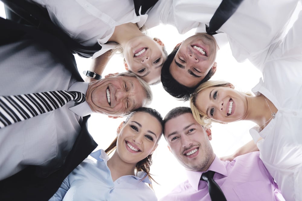 Closeup of happy business people with their heads together representing concept of ftiendship and teamwork isolated on white background.jpeg